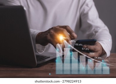 Young man with computer notebook and smartphone hand touching to visualize money growth The phone screen displays graphs and charts showing increasing investment and savings trends, increased account