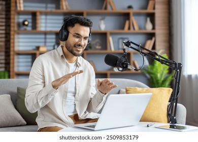 Young man confidently recording podcast at home office, using laptop and microphone setup. Engaging with audience through live streaming with headphones on. Perfect for projects on technology - Powered by Shutterstock