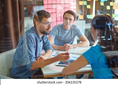 Young Man Consulting His Business Partner At Meeting In Office