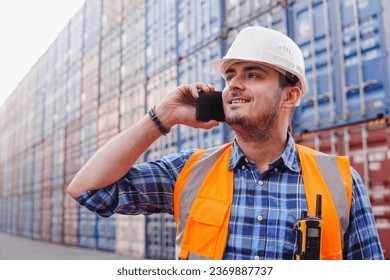 Young man container warehouse worker is making phone call at a shipping yard - Powered by Shutterstock