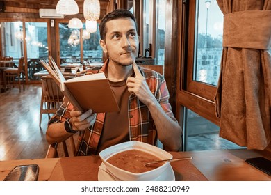 A young man contemplating the menu at a restaurant, deciding on lunch options. - Powered by Shutterstock