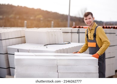 Young man contractor builder is holding an autoclaved aerated concrete block aac on a construction site.