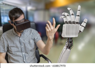 Young man is controlling robotic hand with virtual reality headset.