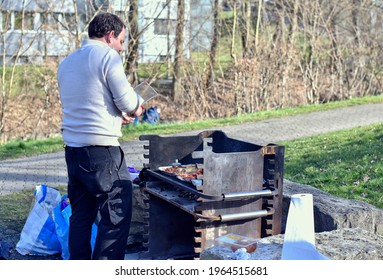 Young man cooking barbeque on grill outdoors