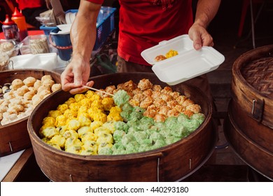 Young man cooking chinese traditional steamed buns at the street food stall in Chinatown, Kuala Lumpur, Malaysia.