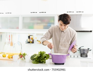 Young Man Cooking At Home In Kitchen
