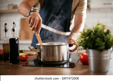 Young man cooking lunch at home. Handsome man preparing delicious food. 