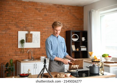 Young Man Cooking Rice With Mushrooms While Following Video Tutorial In Kitchen