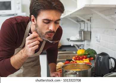 Young Man Cooking Romantic Dinner At Home Taste Soup