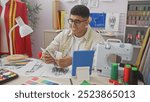 A young man counting egyptian pounds in a vibrant tailor shop filled with sewing supplies and colorful fabrics.