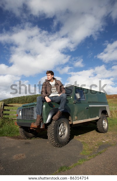 Young man in countryside with\
SUV