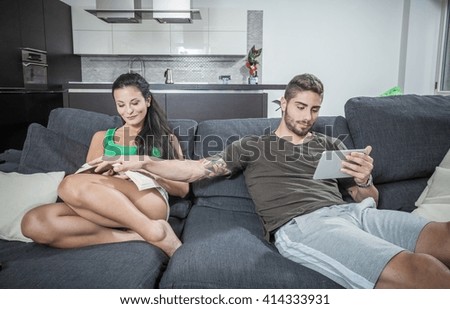 Young man covering girlfriends book on sofa