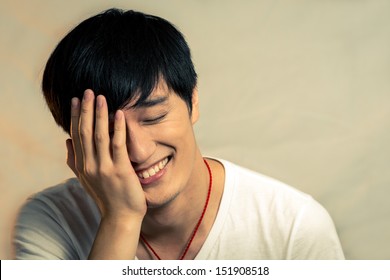 Young man covering his face and smiling, with fashion tone
