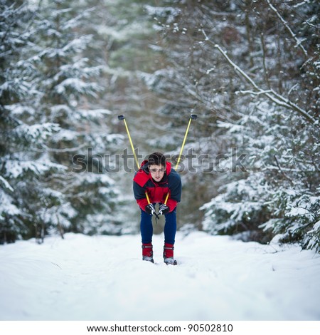 young man cross-country skiing on a snowy forest trail (color toned image)
