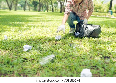 Young man crouching to waste and picking it up in bin bag