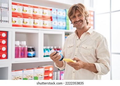 Young Man Customer Using Smartphone Holding Medicine Bottle At Pharmacy