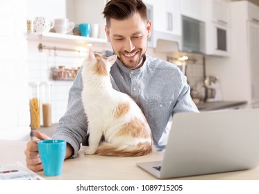 Young Man With Cute Cat And Laptop At Home