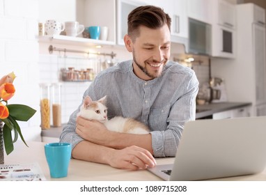 Young Man With Cute Cat And Laptop At Home