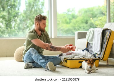 Young man with cute dog packing suitcase at home - Powered by Shutterstock