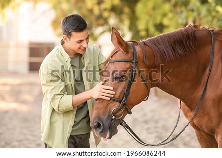 Young man with cute horse outdoors