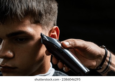 Young man cutting hair at barbershop, barber at work, trimmer - Powered by Shutterstock