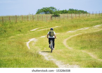 Young Man Cycling Up A Hill In The South Downs National Park, Sussex, Uk