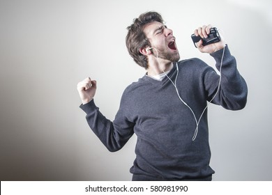 Young Man Dancing And Singing To The Music On His Mobile Phone Through Earphones, Goofy And Happy