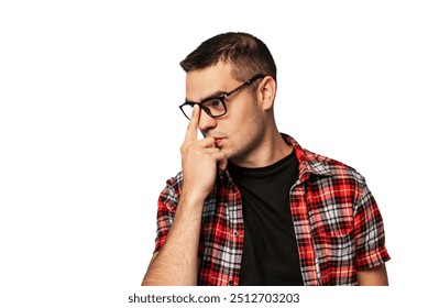 Young man deep in thought wearing glasses and a plaid shirt. A young man with glasses in a plaid shirt touches his face, appearing lost in thought against a plain background. - Powered by Shutterstock