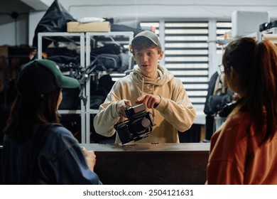 Young man demonstrating camera usage to peers in workshop setting, engaging in learning process. Enthusiastic participants observing and discussing camera functions in detail - Powered by Shutterstock