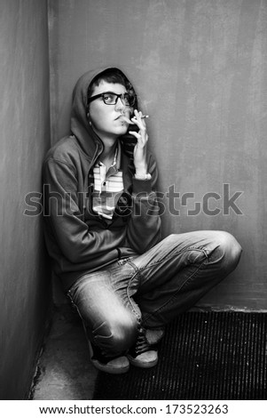 young guy in a shirt smokes on the street