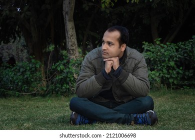 young man different moods of expression cross leg sitting in a park from flat angle