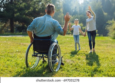 Young Man With Disabilities Waving Hello To His Family