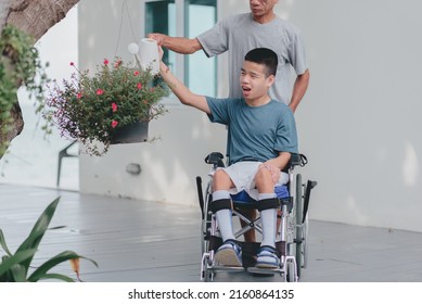 Young Man With Disability And Father Water The Plants In The Garden, Family Is Support To Develop Skills For Life And Happy, Hobby And Rehabilitation With Natural Therapy And Mental Health Concept.