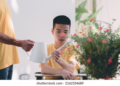 Young Man With Disability And Father Water The Plants In The Garden, Family Is Support To Develop Skills For Life And Happy, Hobby And Rehabilitation With Natural Therapy And Mental Health Concept.