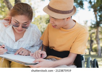 Young Man With Disability And Parent Or Teacher Or Volunteer Or Caregiver Relaxing And Learning Activities With Family At The Outdoor Vacation In Summer, People In The Park And Mental Health Concept