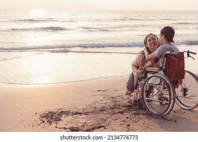 Young man with disability and parent or volunteer or caregiver smiling and singing, playing ukulele on the beach,Vacation on holiday with family activity and natural therapy and mental health concept.