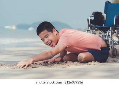 Young Man With Disability Relax And Practice Small Muscle Skills Through Sand Play And Large Muscles Skills Through Crawling On The Beach In Summer, Outdoor Natural Therapy And Mental Health Concept.