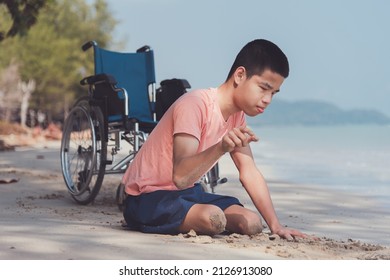 Young Man With Disability Relax And Practice Small Muscle Skills Through Sand Play And Large Muscles Skills Through Crawling On The Beach In Summer, Outdoor Natural Therapy And Mental Health Concept.