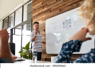 Young Man Discussing New Mobile Application Design On White Board With Colleagues During A Meeting. Business Presentation In Boardroom.