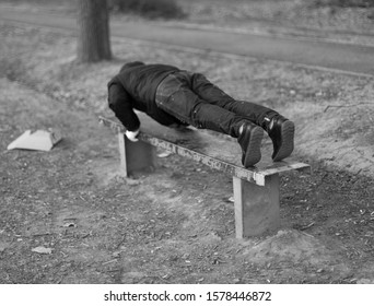 A young man does push ups on an iron park bench as he warms up for his daily workout or jogging