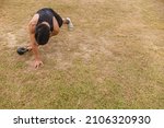 A young man does a set of Kettlebell plank drags. Advanced core and oblique workout. Training at an outdoor field.