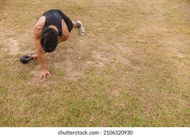 A young man does a set of Kettlebell plank drags. Advanced core and oblique workout. Training at an outdoor field. - Powered by Shutterstock