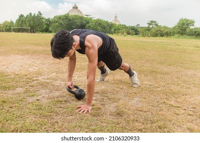 A young man does a set of Kettlebell plank drags. Advanced core and oblique workout. Training at an outdoor field. - Powered by Shutterstock