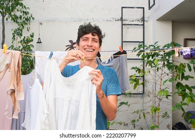 Young man does work at home, hangs clothes on clothesline.