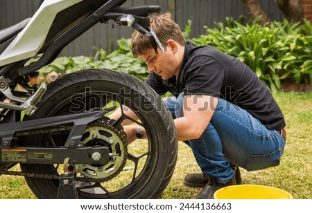 Young man doing back yard motorcycle maintenance.