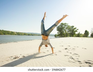 Young Man Doing A Cartwheel On The Beach