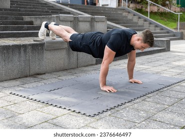 Young man doing a decline push-up or elevated push-up on concrete background outdoors - Powered by Shutterstock