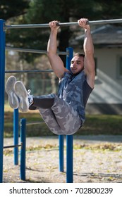 Young Man Doing Exercise With Dips Bar in City Park Area - Training and Exercising for Endurance - Healthy Lifestyle Concept Outdoor