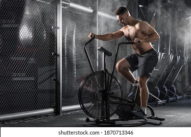 Young Man doing Exercise on Spin Bike in dark Fitness Gym. Healthy Lifestyle and Sport Concepts. Functional training. - Shutterstock ID 1870713346