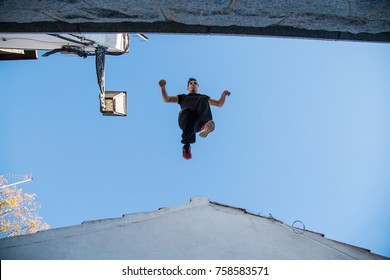 Young Man Doing Impressive parkour Jump From One Roof To Another. 